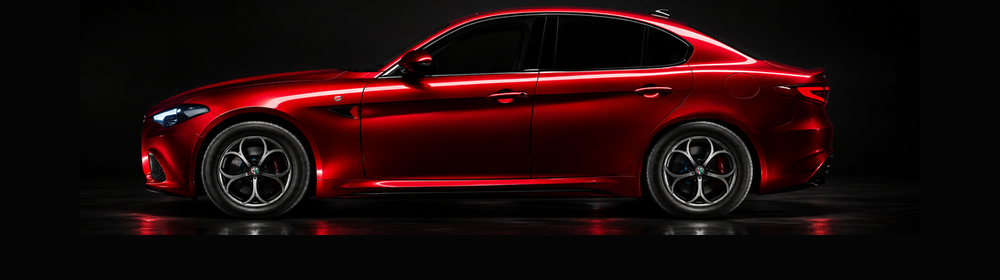 Piros sportos Alfa Romeo oldalnézetben, sötét műtermi háttér előtt